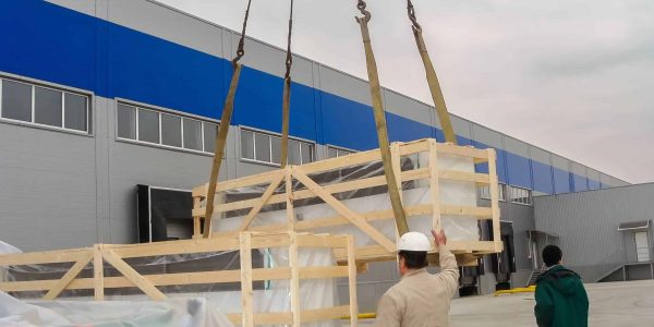 crane-unloads-large-wooden-crate-as-workers-oversee-process-outside-warehouse (1)